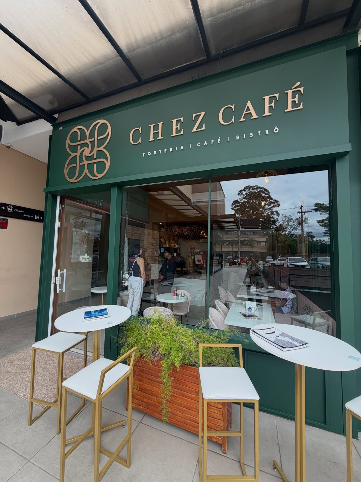 Fachada verde do Chez Café com letreiro dourado